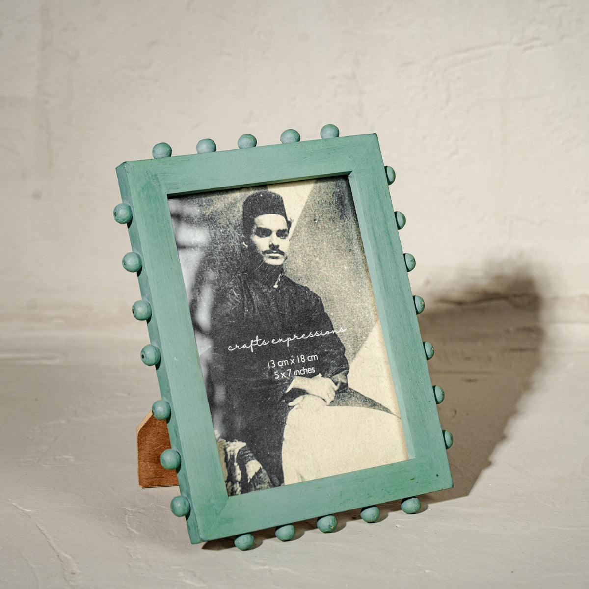 Aqua green beaded wooden tabletop photo frame holding a 5 by 7 inch photograph