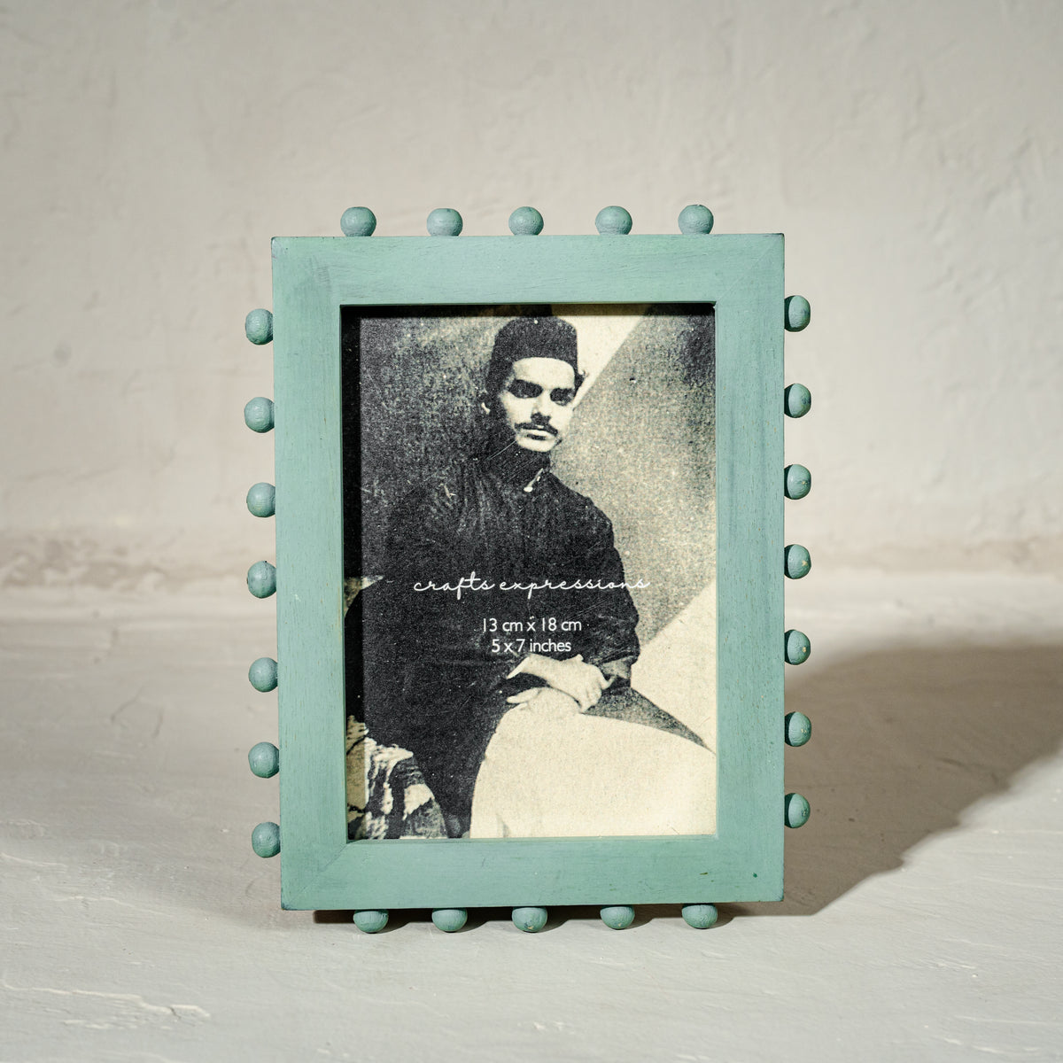 Aqua green beaded wooden tabletop photo frame holding a 5 by 7 inch photograph