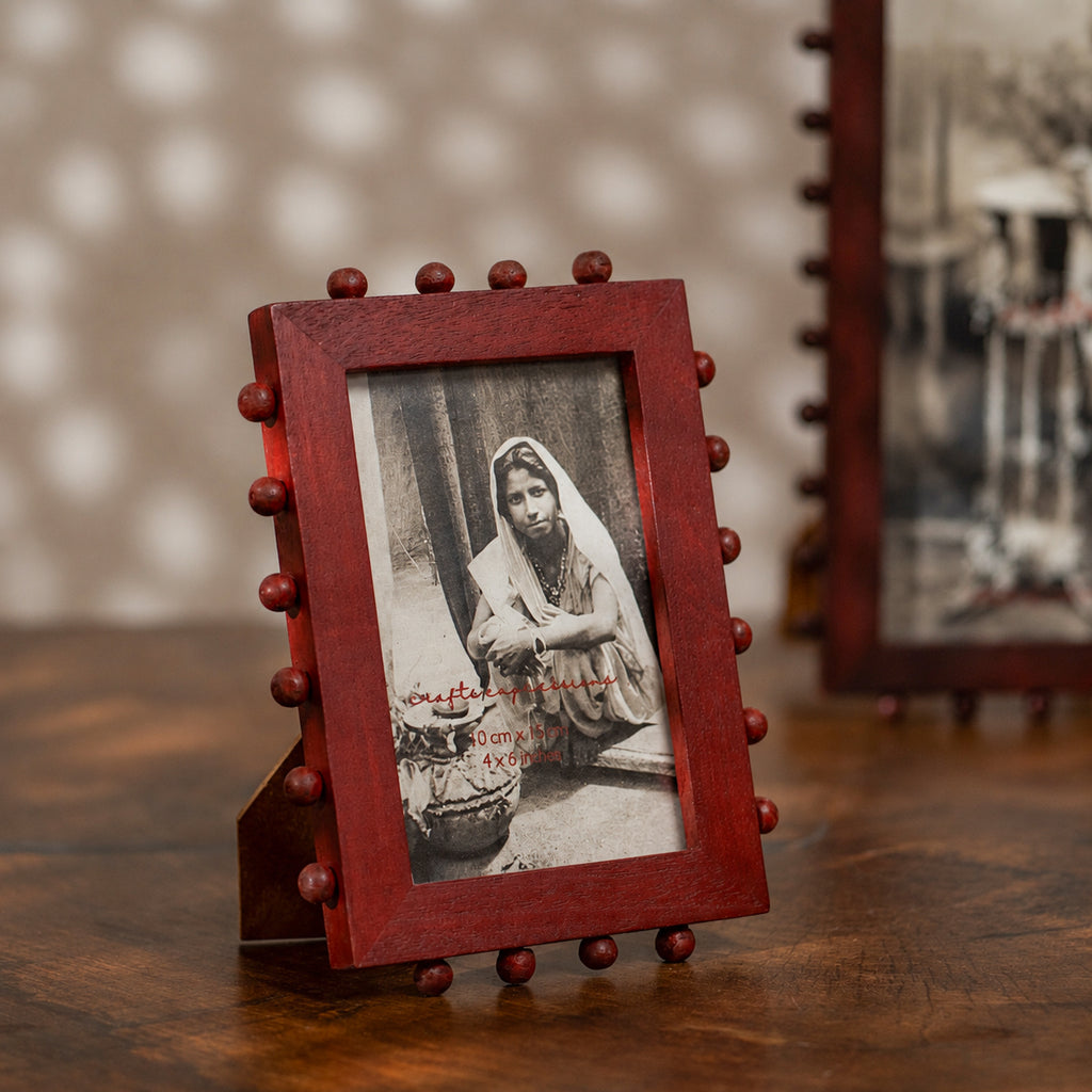 Red beaded wooden tabletop photo frame holding a 4 by 6 inch photograph