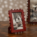 Red beaded wooden tabletop photo frame holding a 4 by 6 inch photograph