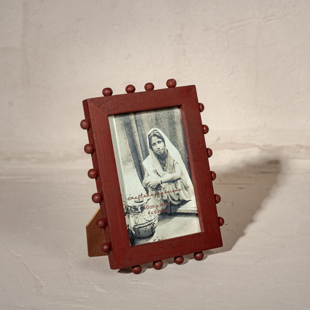 Red beaded wooden tabletop photo frame holding a 4 by 6 inch photograph