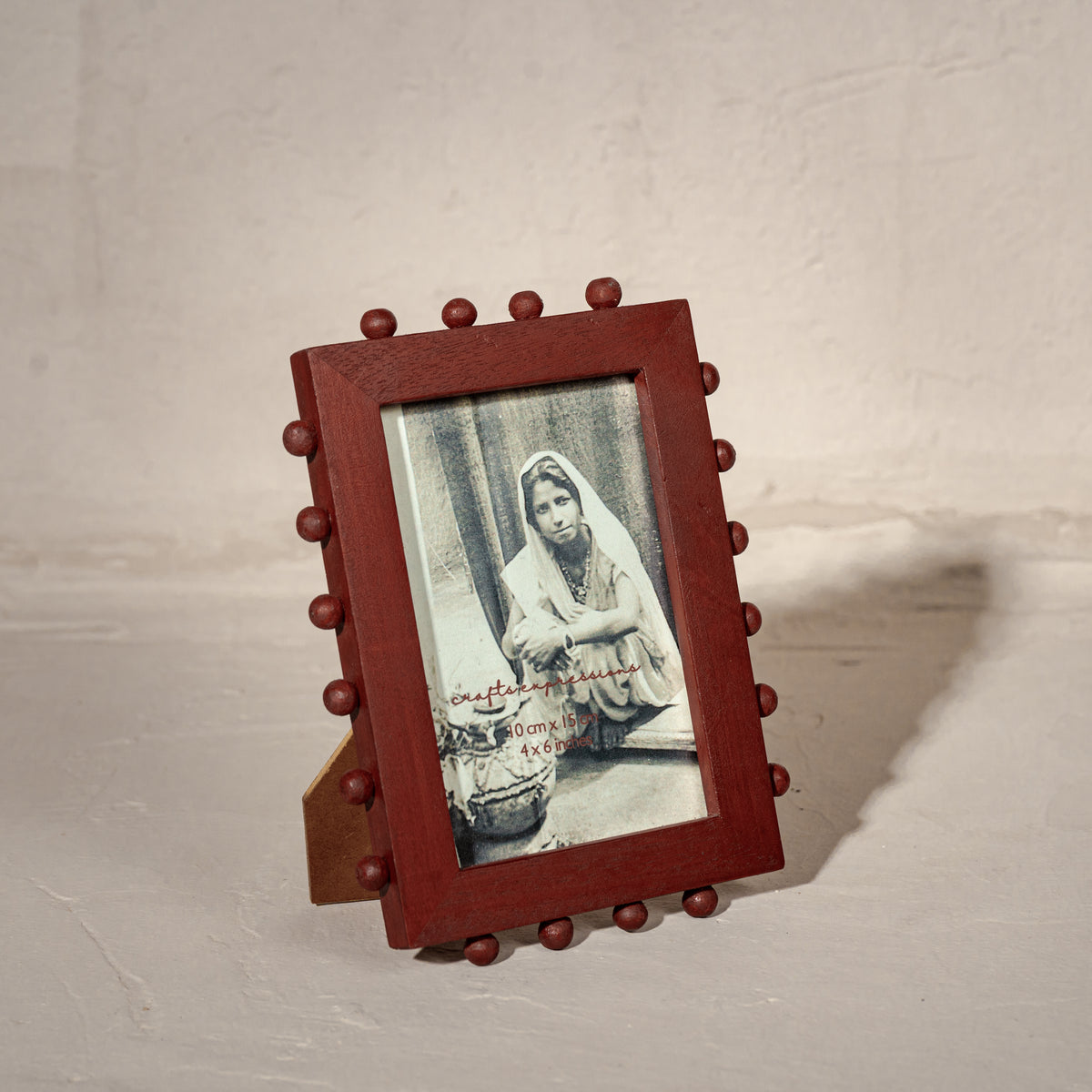Red beaded wooden tabletop photo frame holding a 4 by 6 inch photograph