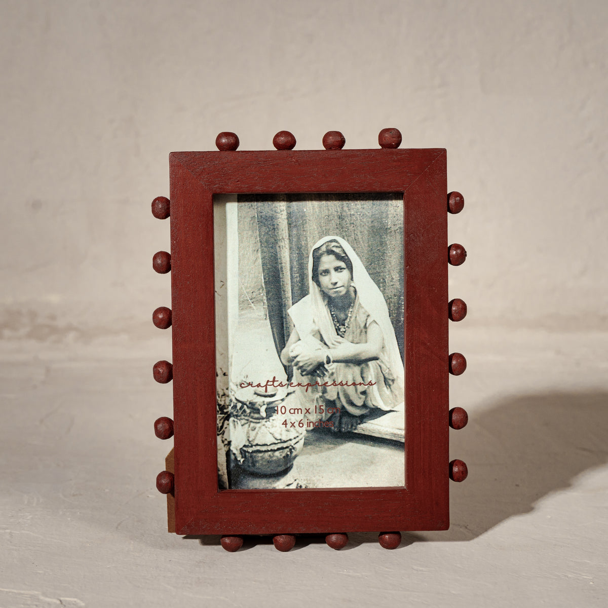 Red beaded wooden tabletop photo frame holding a 4 by 6 inch photograph