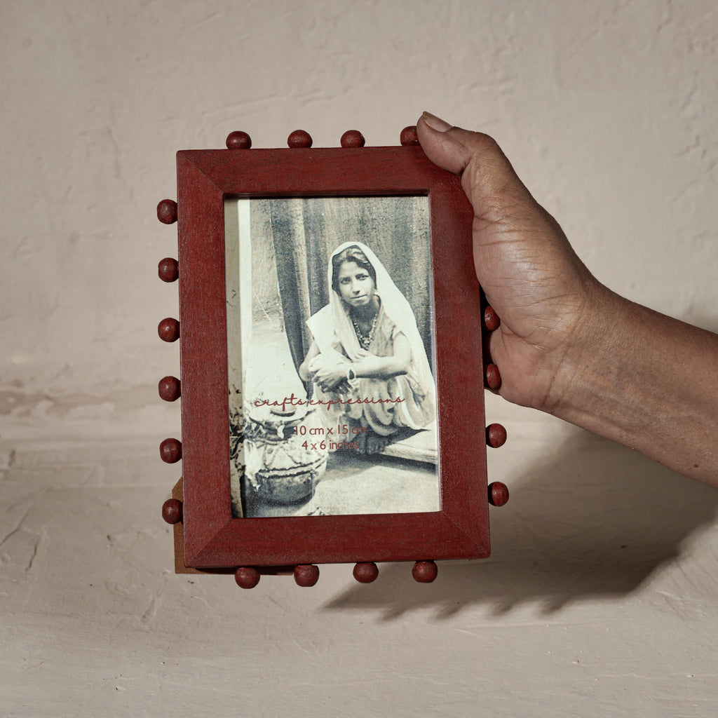 Red beaded wooden tabletop photo frame holding a 4 by 6 inch photograph