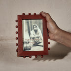 Red beaded wooden tabletop photo frame holding a 4 by 6 inch photograph