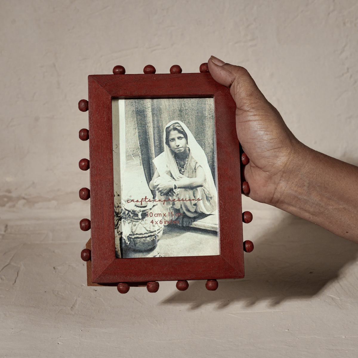 Red beaded wooden tabletop photo frame holding a 4 by 6 inch photograph