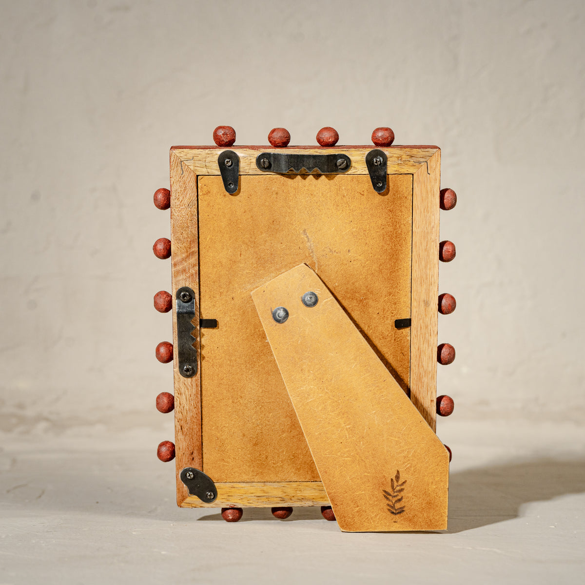 Red beaded wooden tabletop photo frame holding a 4 by 6 inch photograph