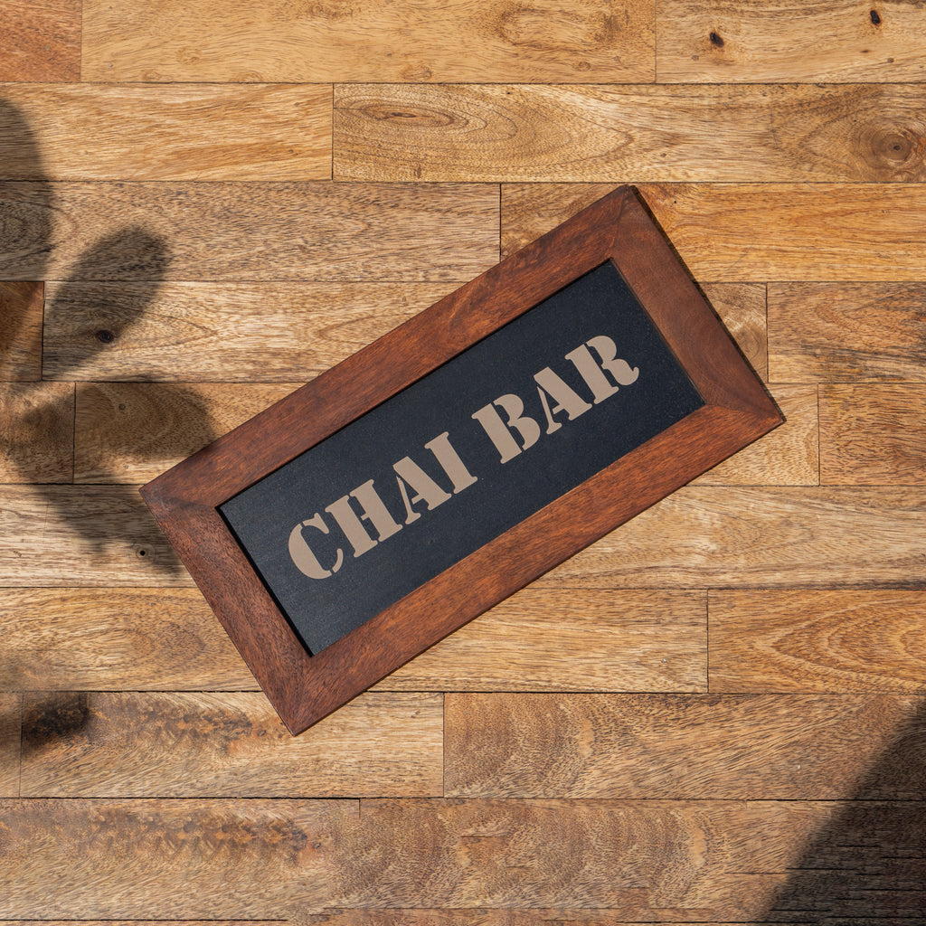 Top view of the framed Chai Bar sign on a wooden surface