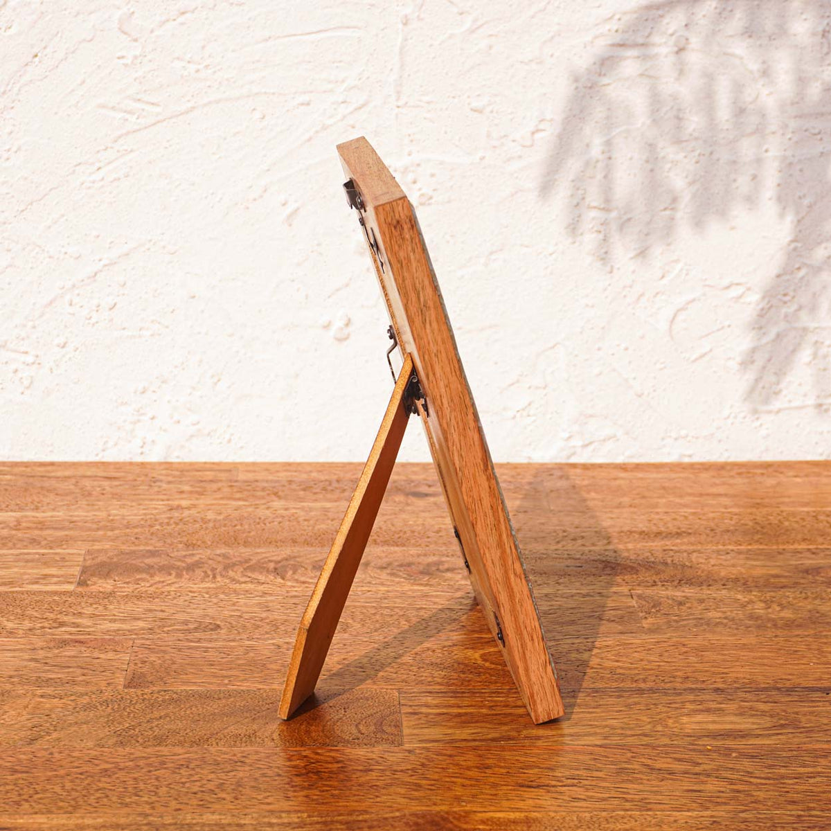Side view of the Morning Love wooden photo frame supported by its easel stand