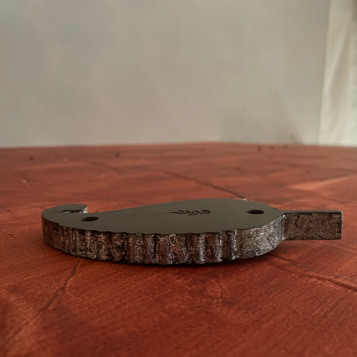 Low side view of a Kairi paisley-shaped wooden wall decoration
