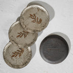 Set of six round wooden coasters with distressed finish and rust botanical motifs