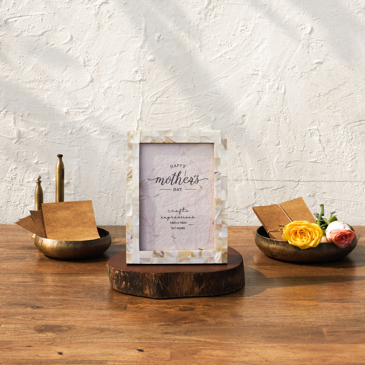 White Mother of Pearl photo frame styled on a wooden riser with flowers