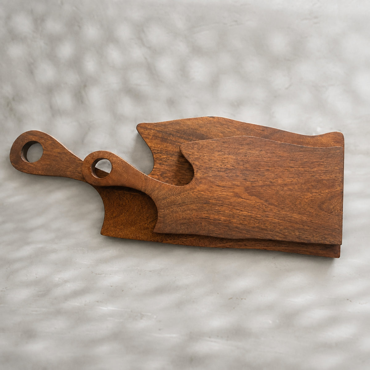 Set of two natural wooden serving boards with sculpted curved cut-outs and handles