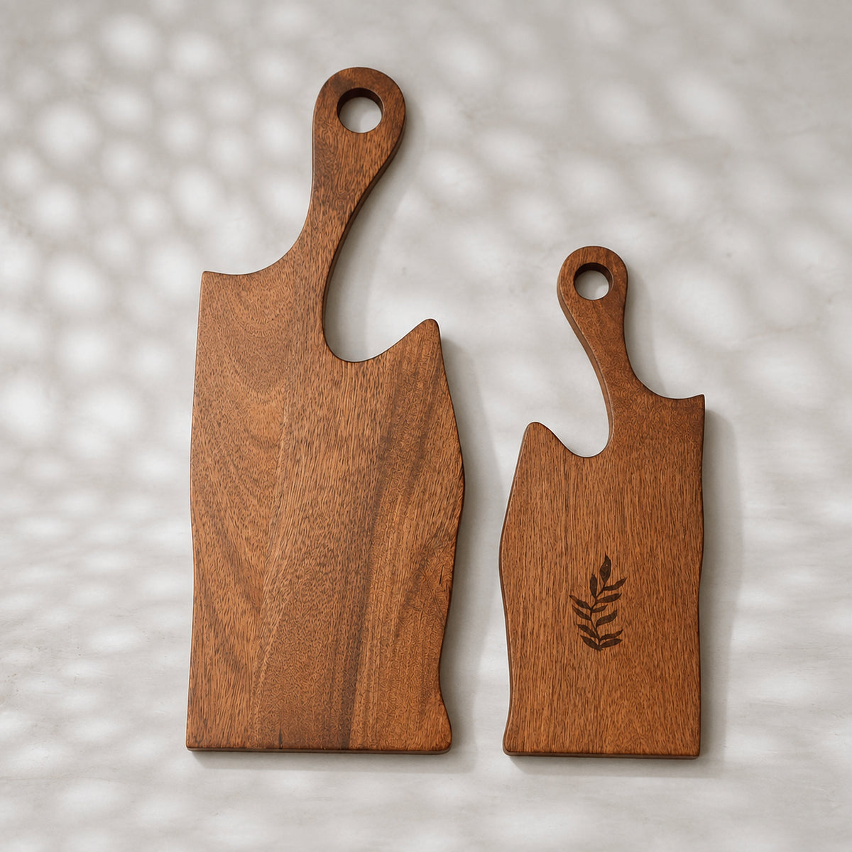 Set of two natural wooden serving boards with sculpted curved cut-outs and handles