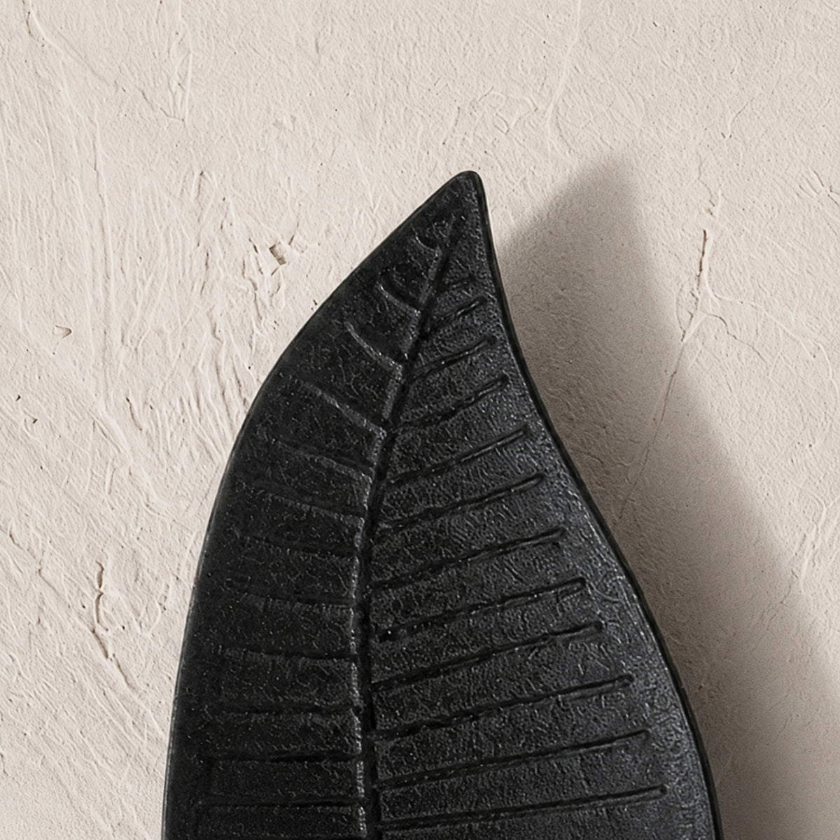 Set of three black wooden leaf-shaped serving platters with carved vein details