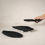 Set of three black wooden leaf-shaped serving platters with carved vein details