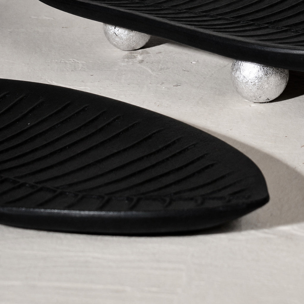 Set of three black wooden leaf-shaped serving platters with carved vein details