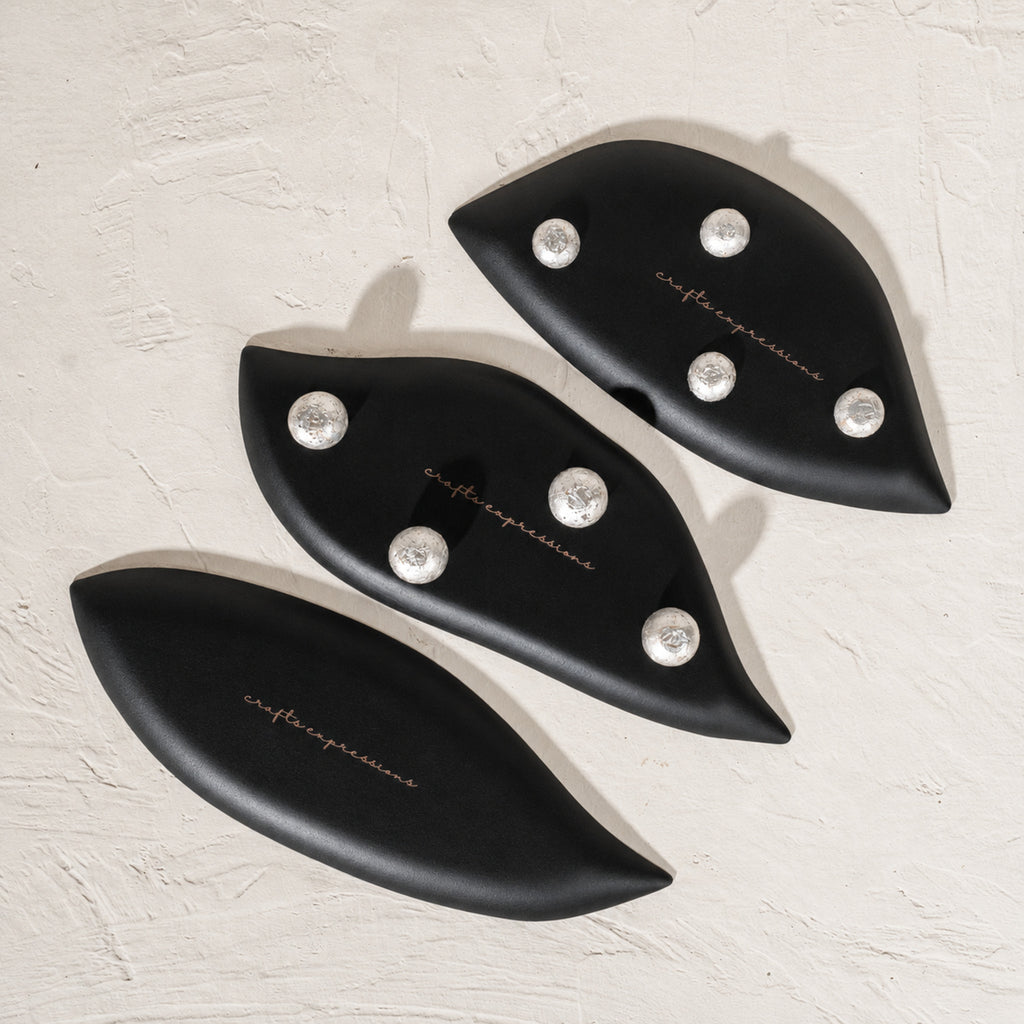 Set of three black wooden leaf-shaped serving platters with carved vein details