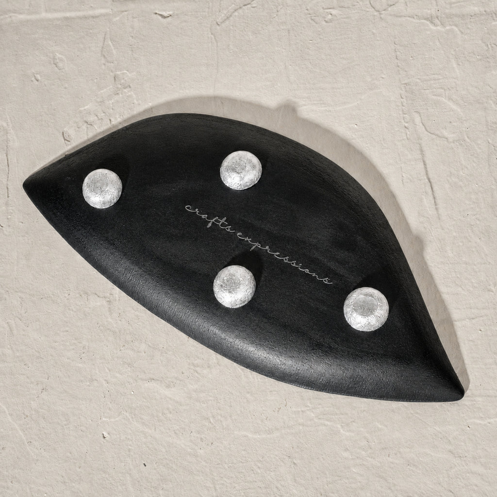 Set of three black wooden leaf-shaped serving platters with carved vein details