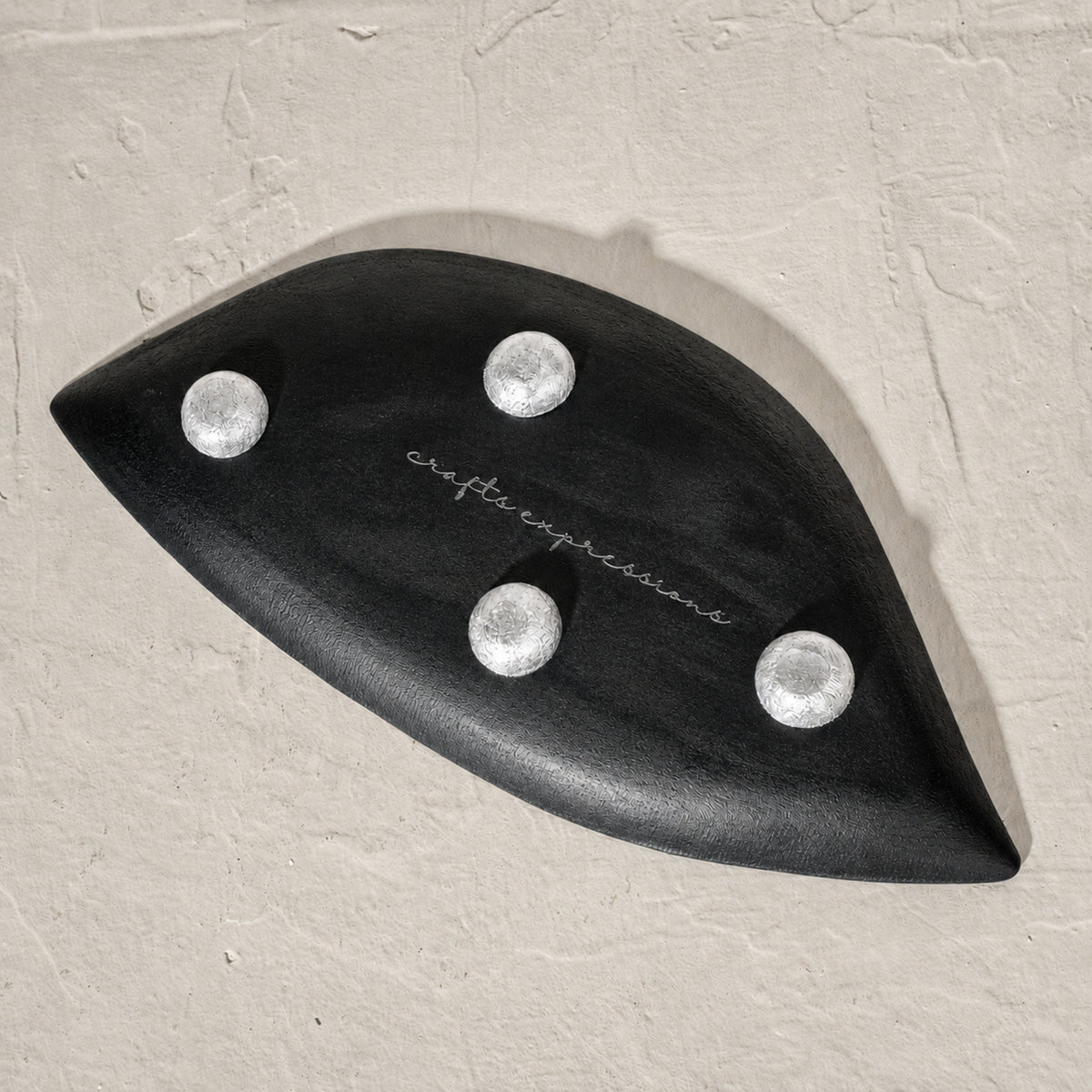 Set of three black wooden leaf-shaped serving platters with carved vein details