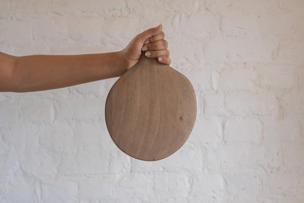Pebble Ash wooden platter held upright in one hand