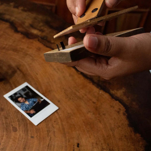 Hands opening the back of a wooden Instax Mini photo frame to insert a print
