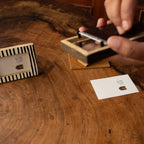 Hands placing an instant photo into a black-and-white striped wooden frame