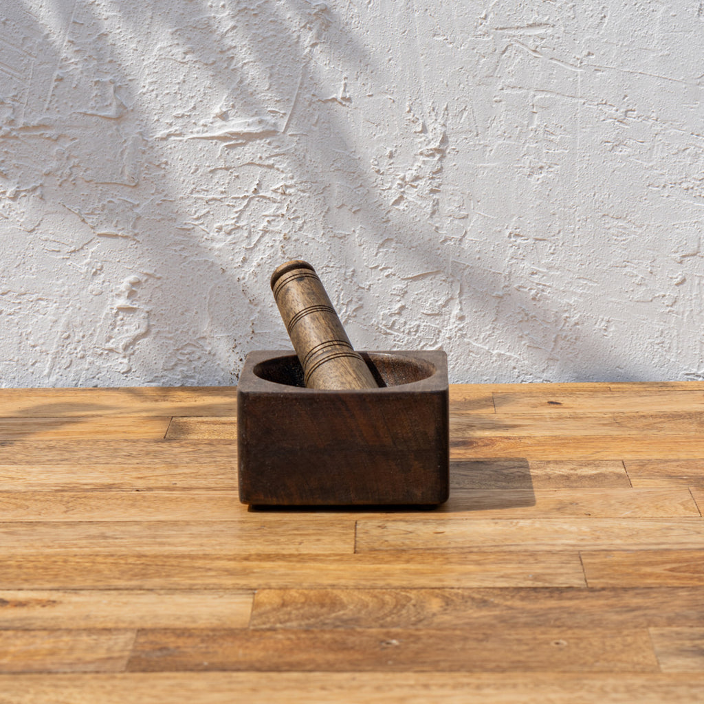 Trunk wooden mortar and pestle standing on a natural wood surface