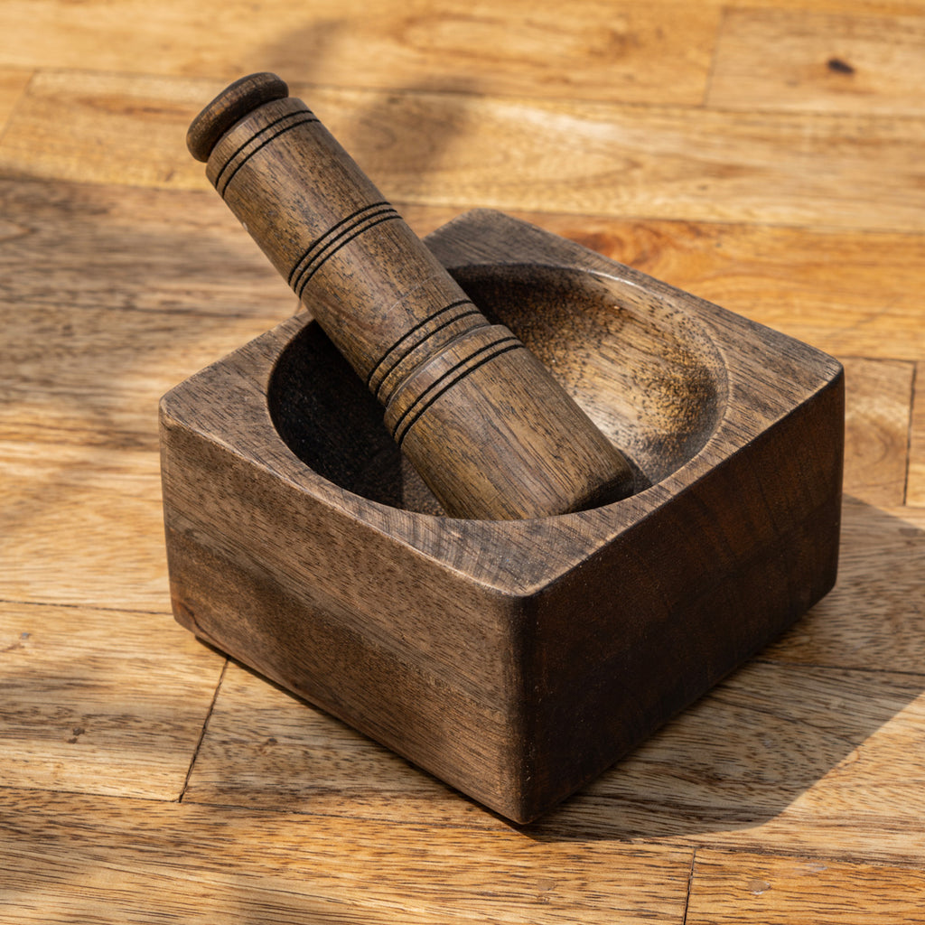 Trunk square wooden mortar with the pestle placed inside