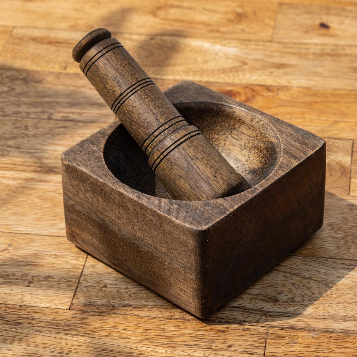 Trunk square wooden mortar with the pestle placed inside