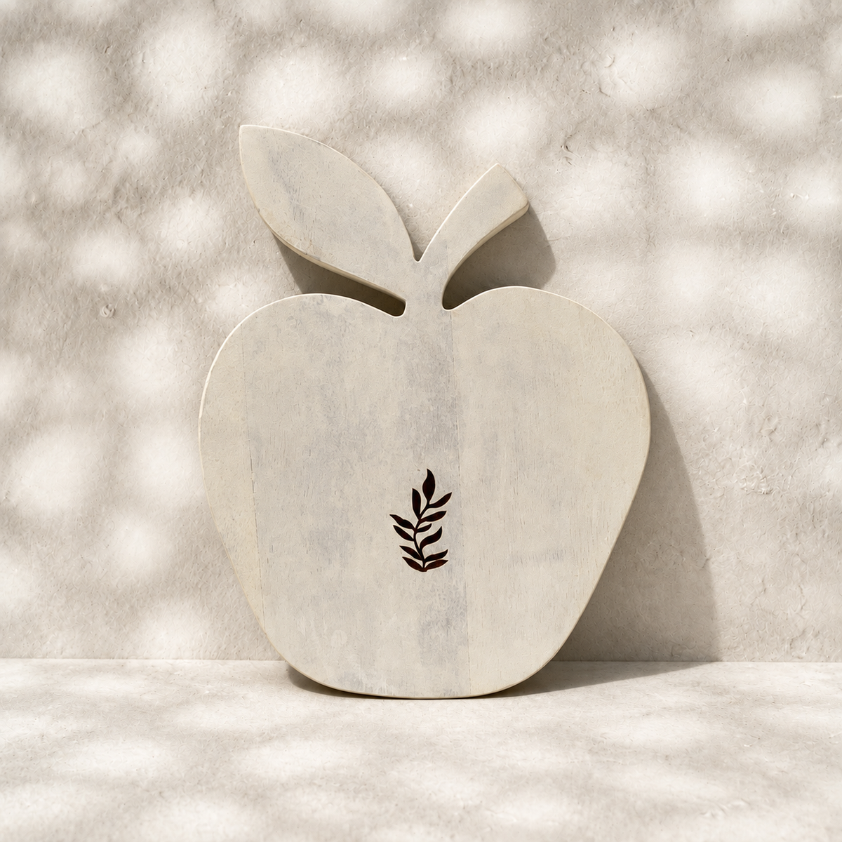 Front view of the whitewashed Orchard apple-shaped trivet with leaf motif