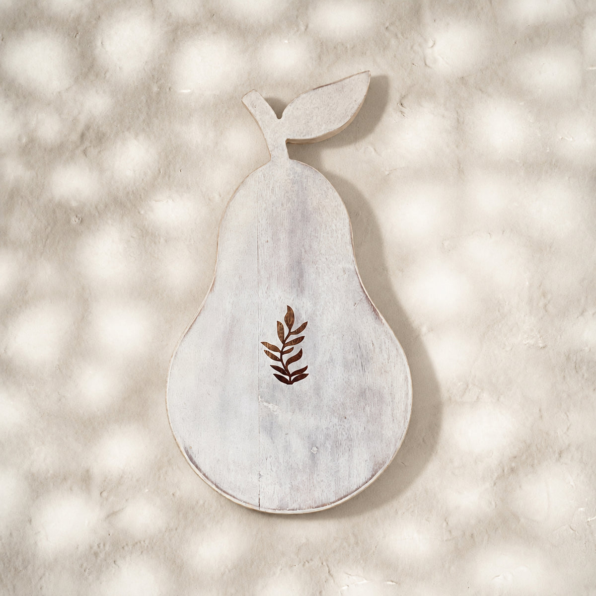 Front view of the whitewashed Orchard pear-shaped trivet with leaf motif