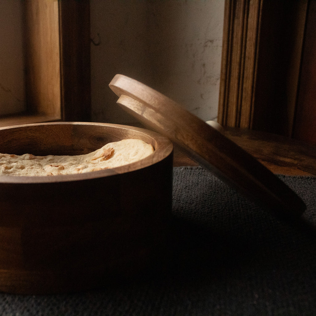 Round wooden roti box displayed open with folded cloth inside