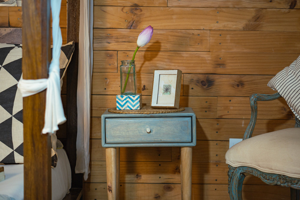 Niche small wooden photo frame displayed on a blue bedside cabinet