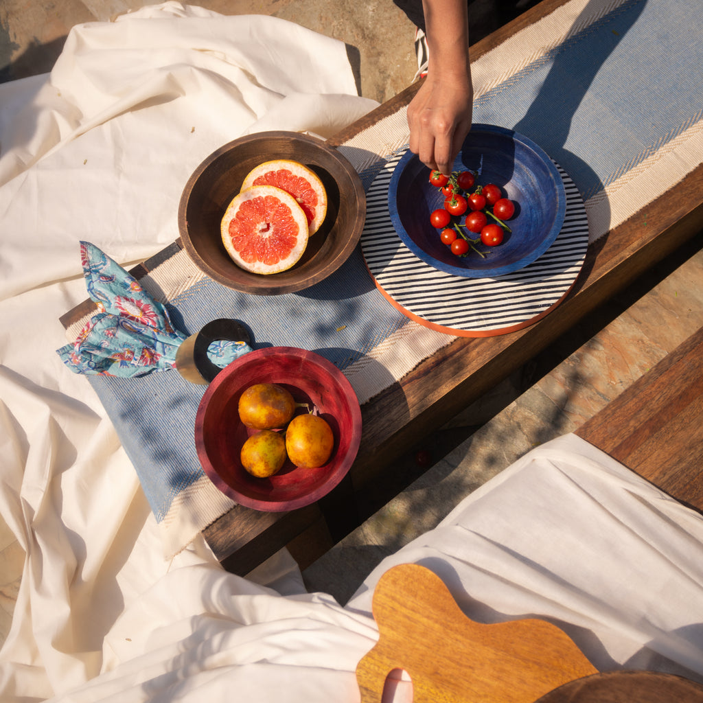 Large wooden bowl set styled with fruit and tableware
