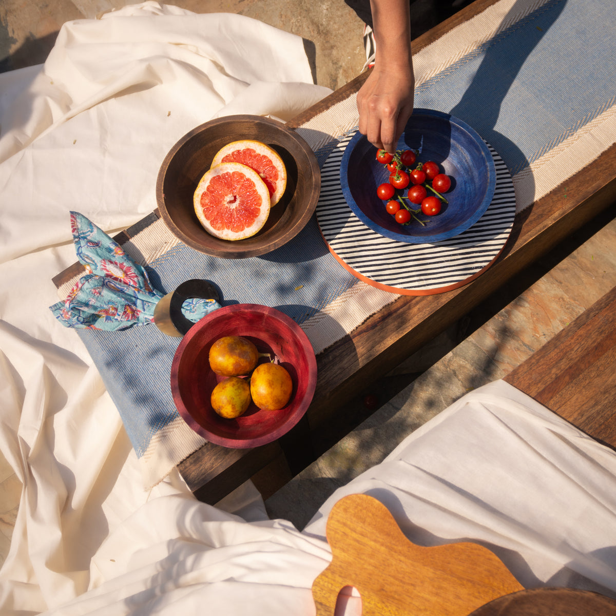 Large wooden bowl set styled with fruit and tableware