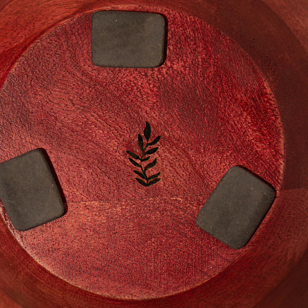 Bottom view of a red wooden bowl with protective pads