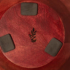 Bottom view of a red wooden bowl with protective pads