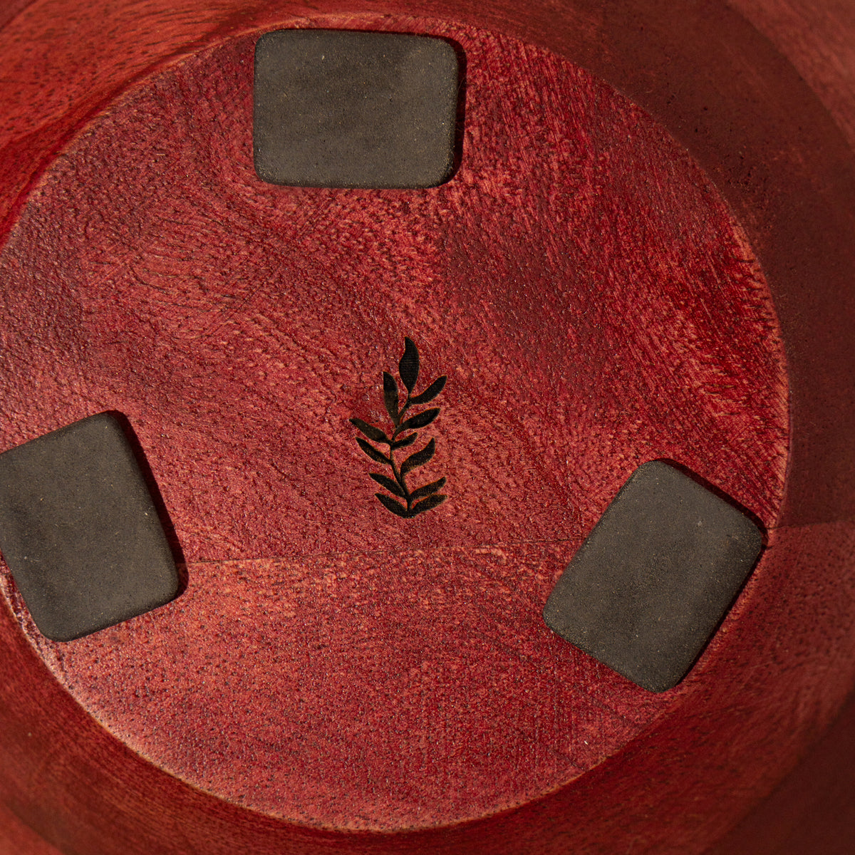 Bottom view of a red wooden bowl with protective pads