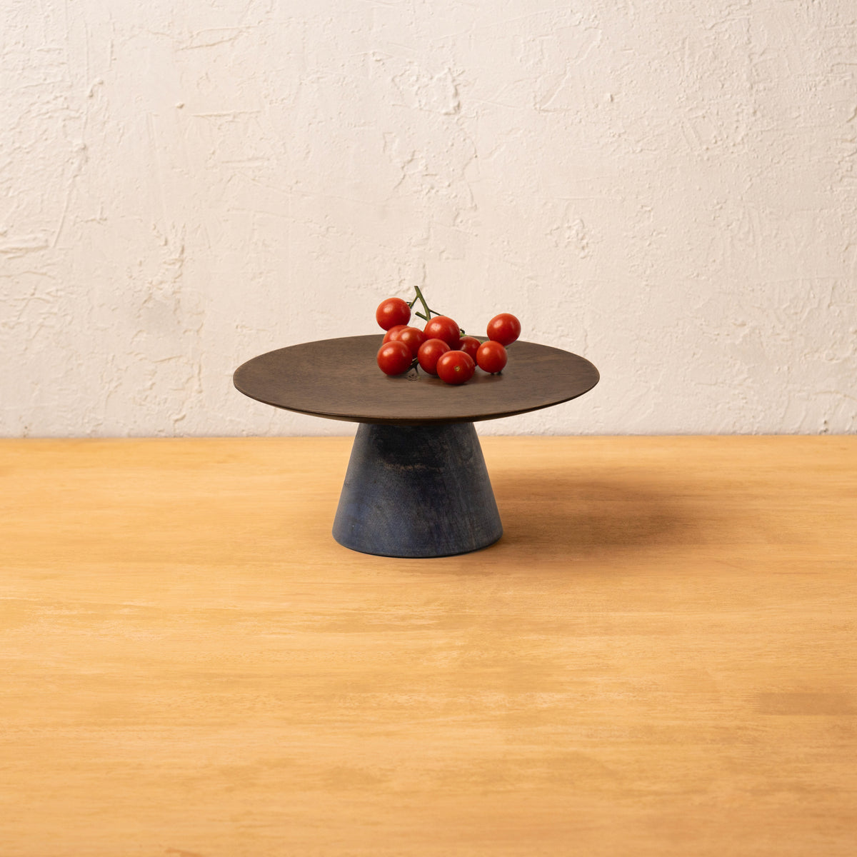 Midnight wooden cake stand holding red tomatoes