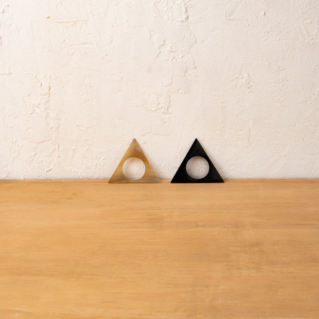 Black and golden Pyramid horn napkin rings displayed upright