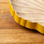 Shell-shaped wooden serving platter placed beneath stacked tableware