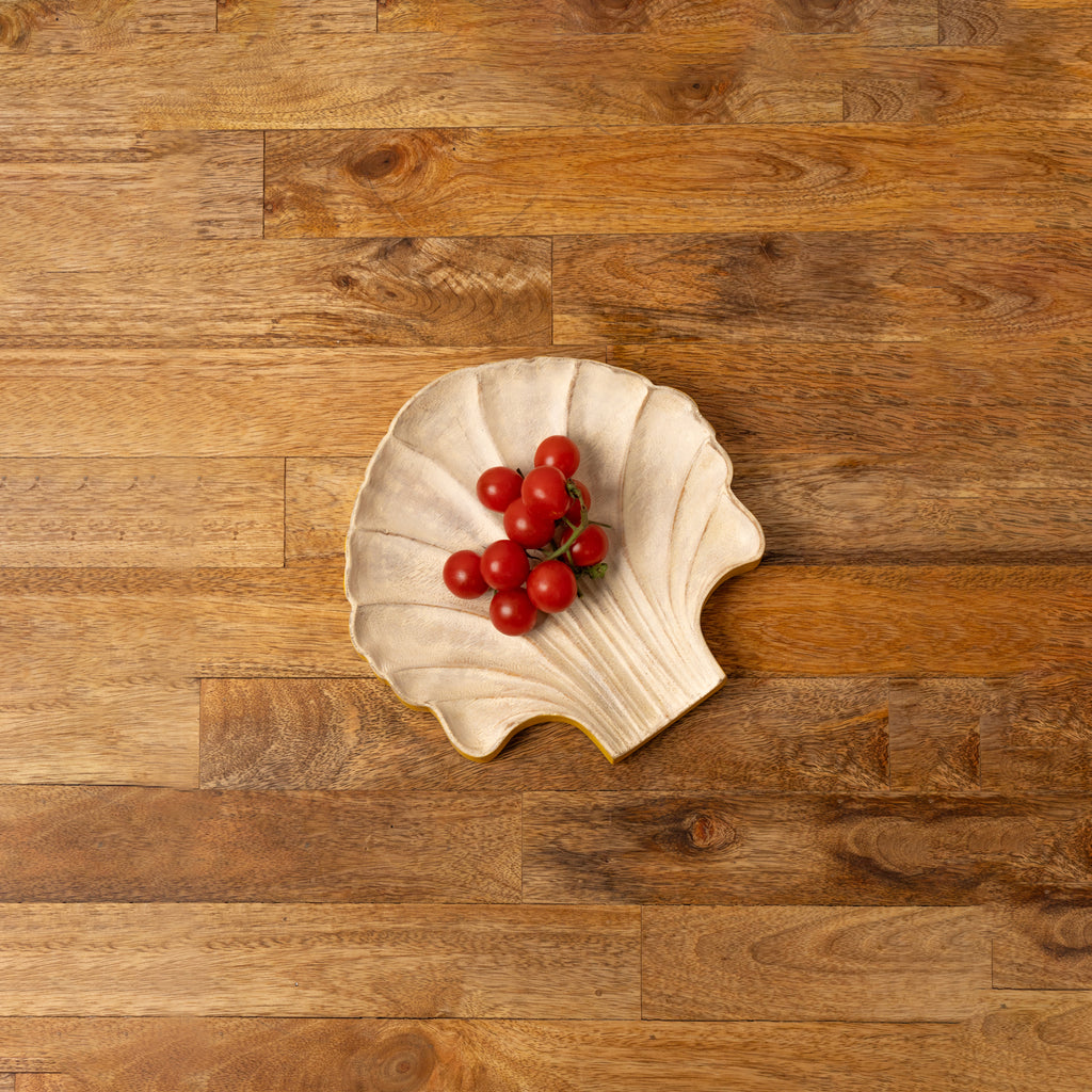 Shell-shaped wooden serving platter holding red berries