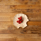Shell-shaped wooden serving platter holding red berries