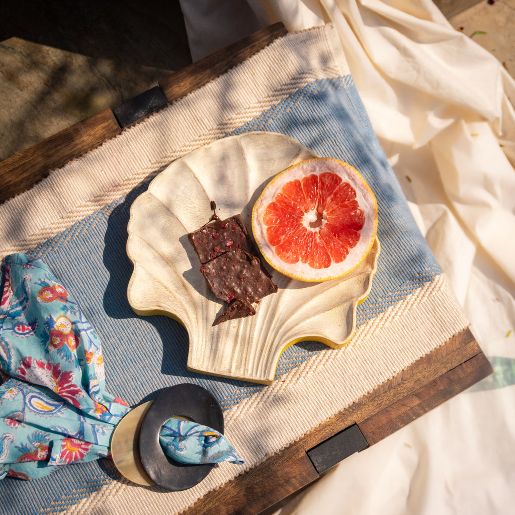 Shell-shaped wooden serving platter styled with bread and fruit