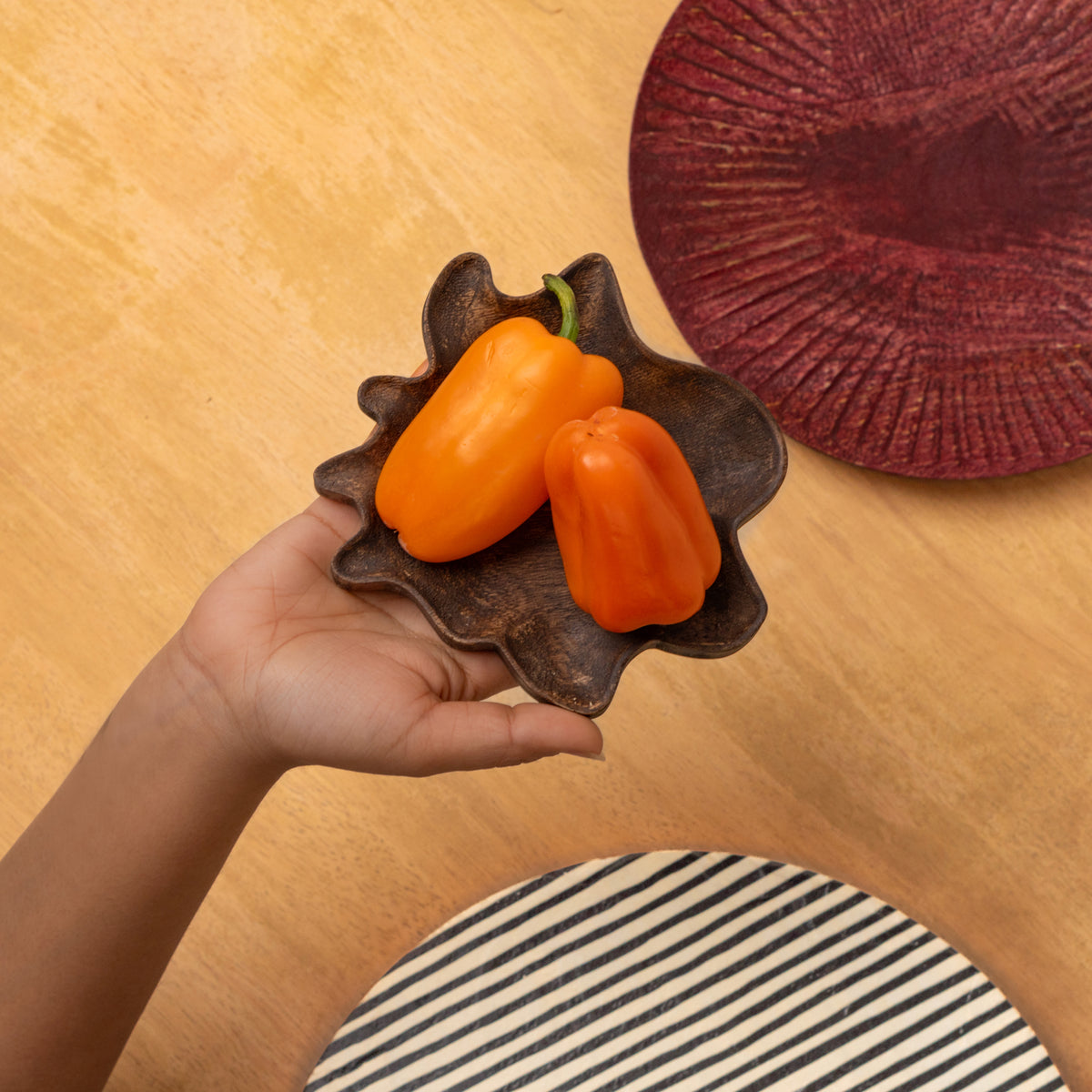 Small Striped wooden platter held in one hand with fruit