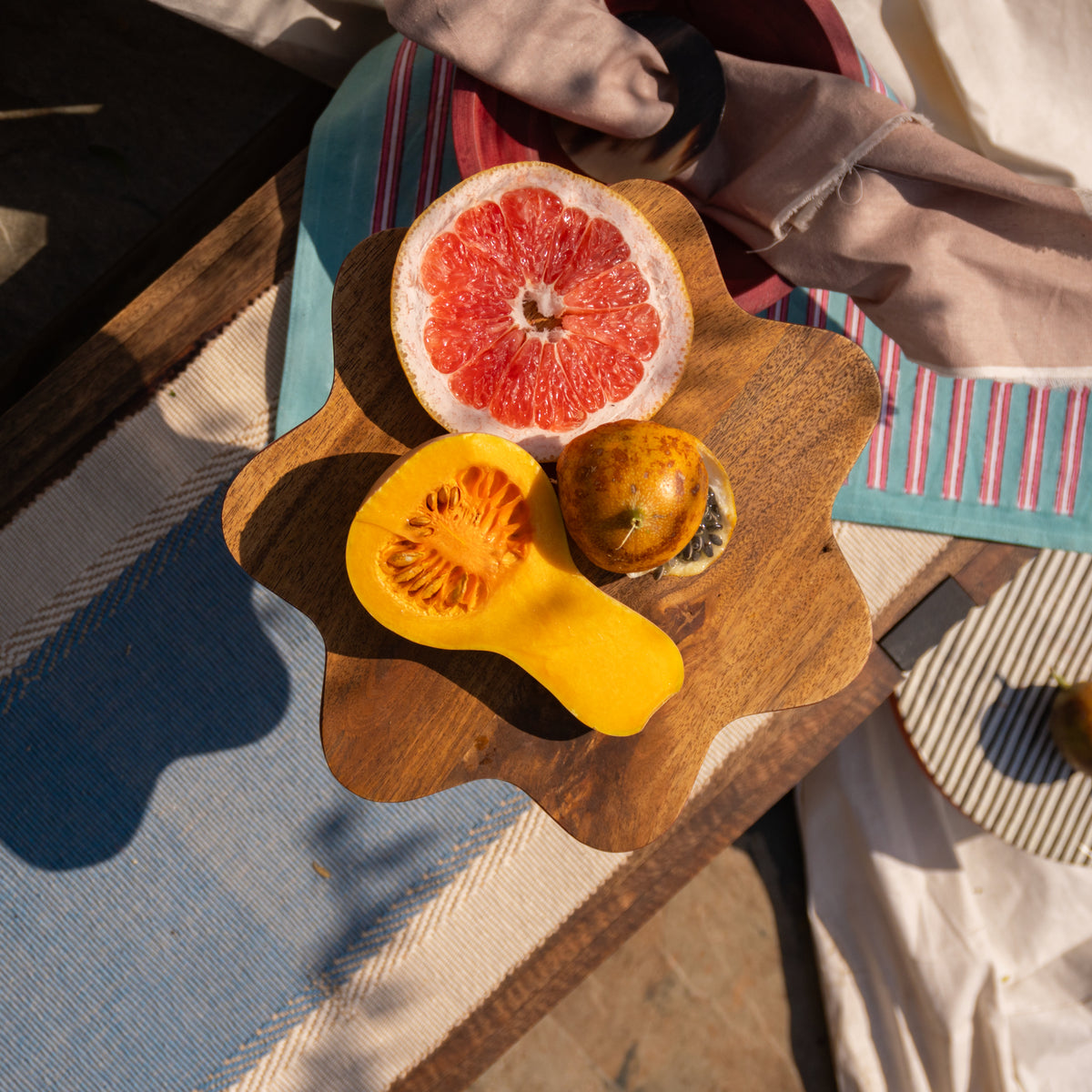 Wavy wooden cake stand styled with fruit on a table