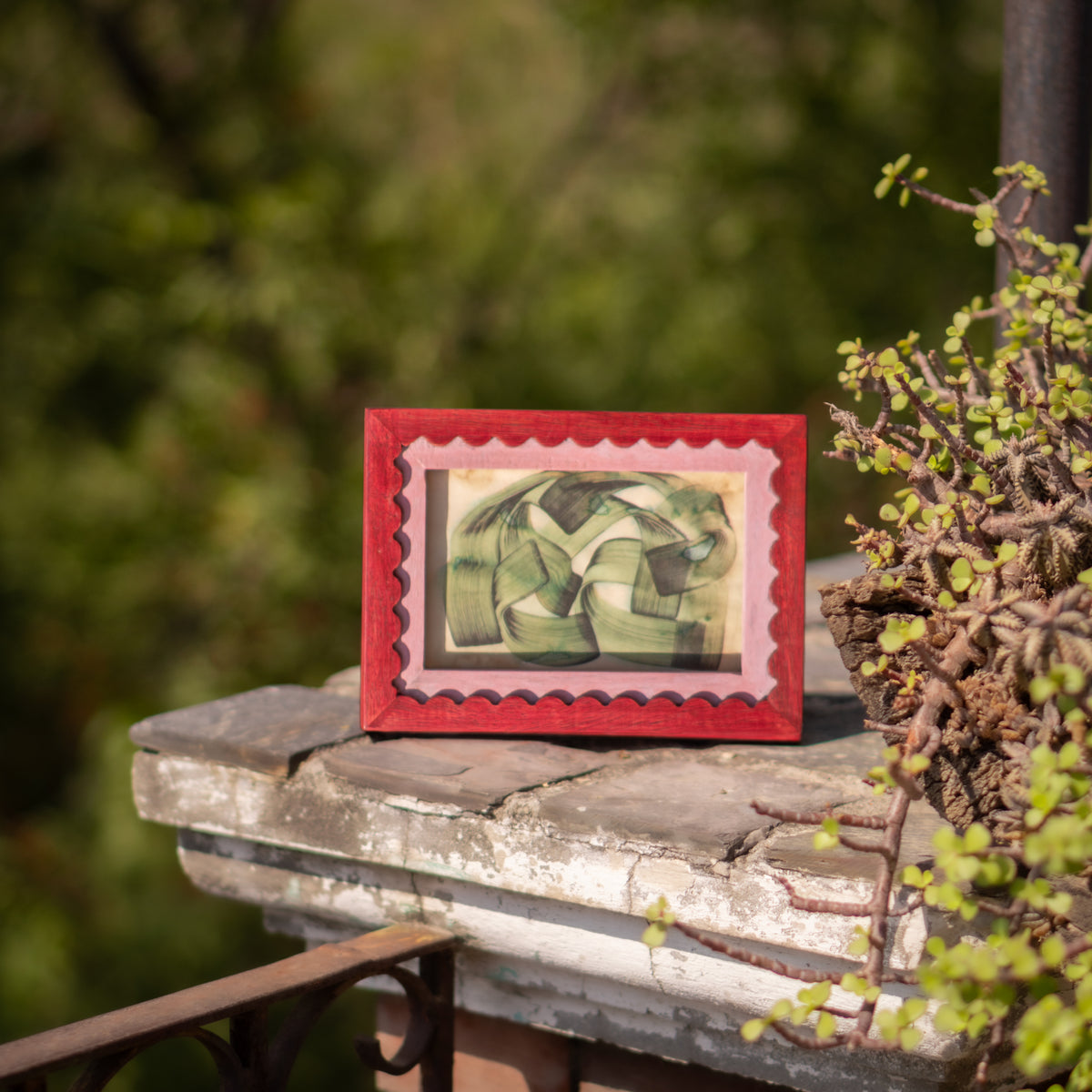 Red wavy wooden photo frame displayed horizontally outdoors