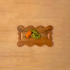 Wavy wooden platter styled with vegetables and fruit