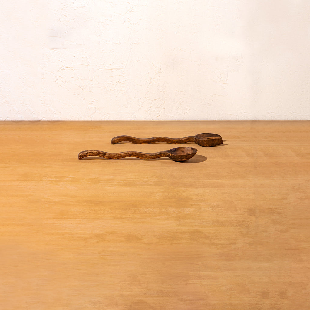 Pair of Wavy wooden salad servers lying on a surface